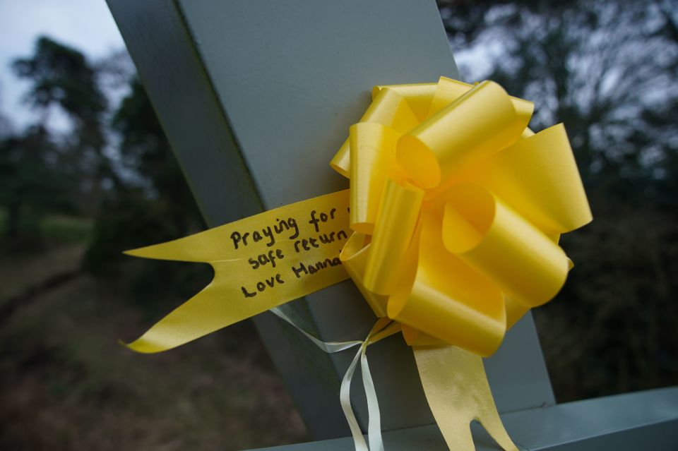 A yellow ribbon with a message of hope written on it is tied to the bridge