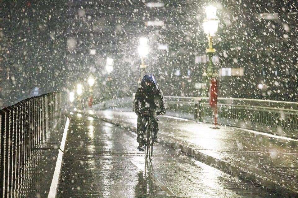 A cyclist makes his way through heavy snowfall on Westminster Bridge, London