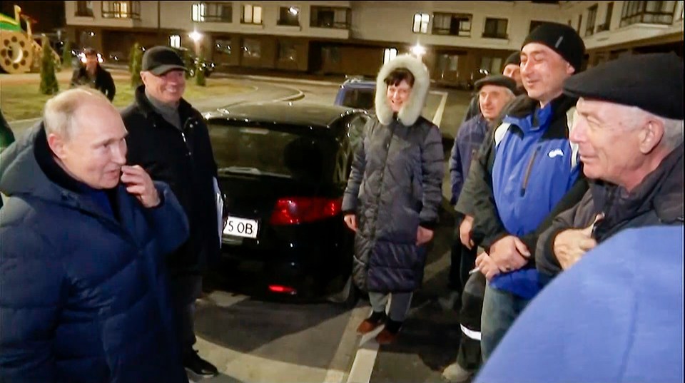 Coward Putin is pictured with locals during his night-time tour of Mariupol