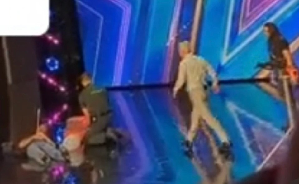 Simon Cowell is down, hit with a fake arrow in his chest