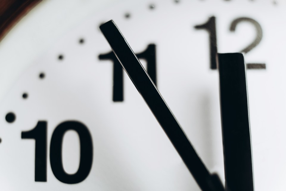 Low angle macro view of round wall clock showing 11:55.