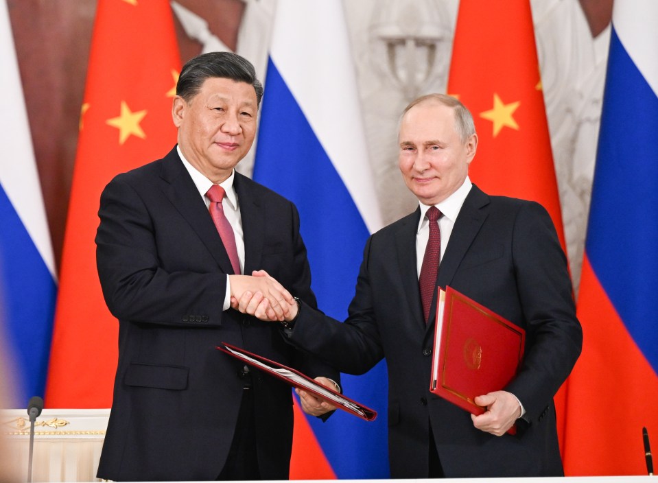 Putin smiles as Xi pulls in his handshake close with his hand on top