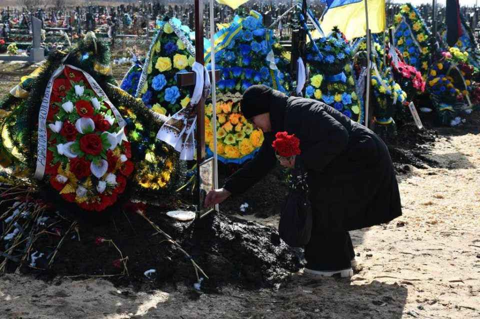 Paraska, 67, laying flowers at her son's grave