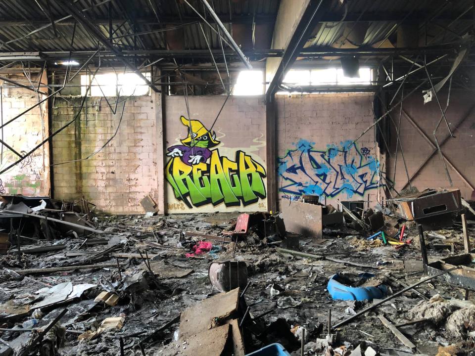 Old chairs have been set on fire while the walls have graffiti on them