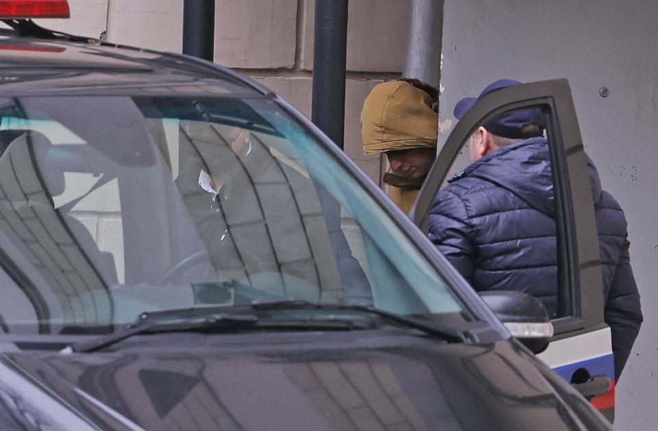 The journalist being led into a car outside a court in Moscow