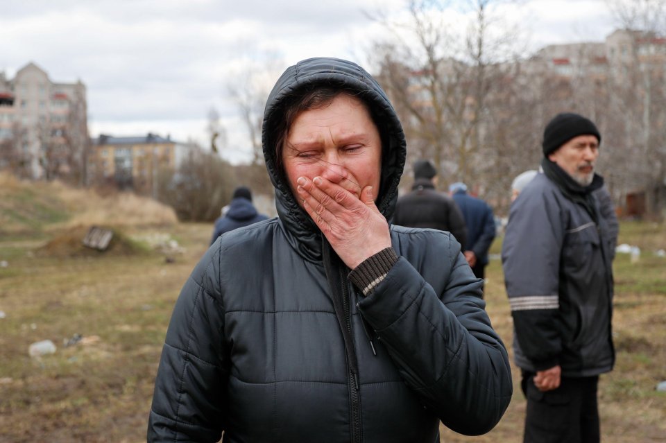 A Ukrainian woman fights back tears in front of a mass grave where dozens of civilians are buried in Bucha