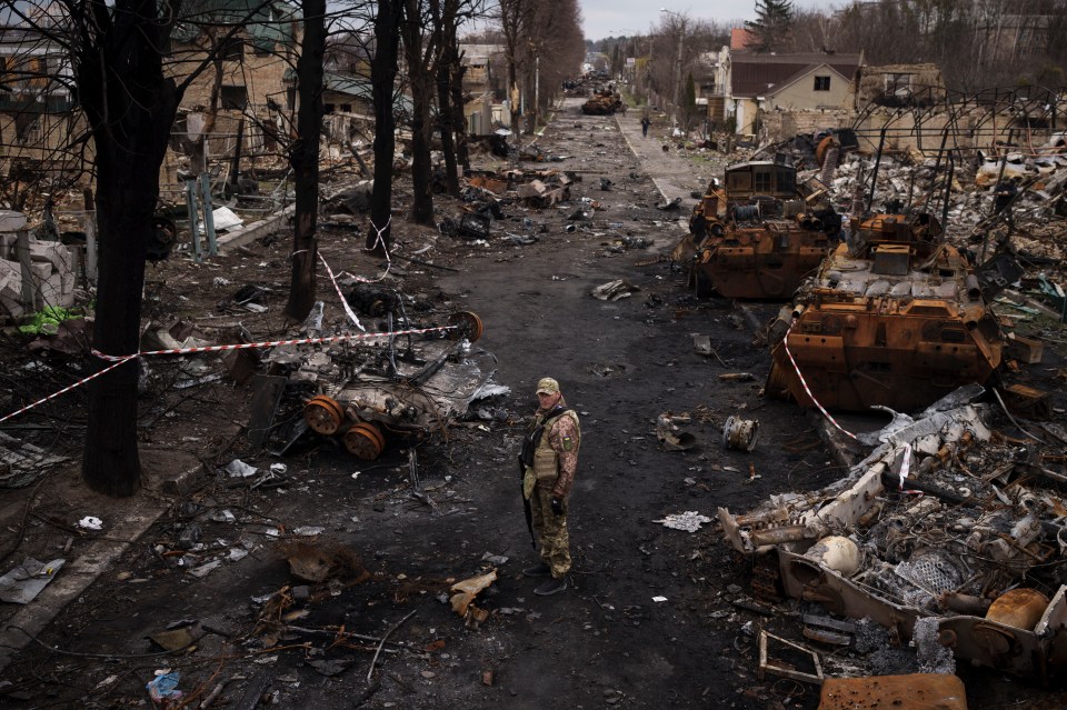 A Ukrainian soldier stands amid total devastation in Bucha