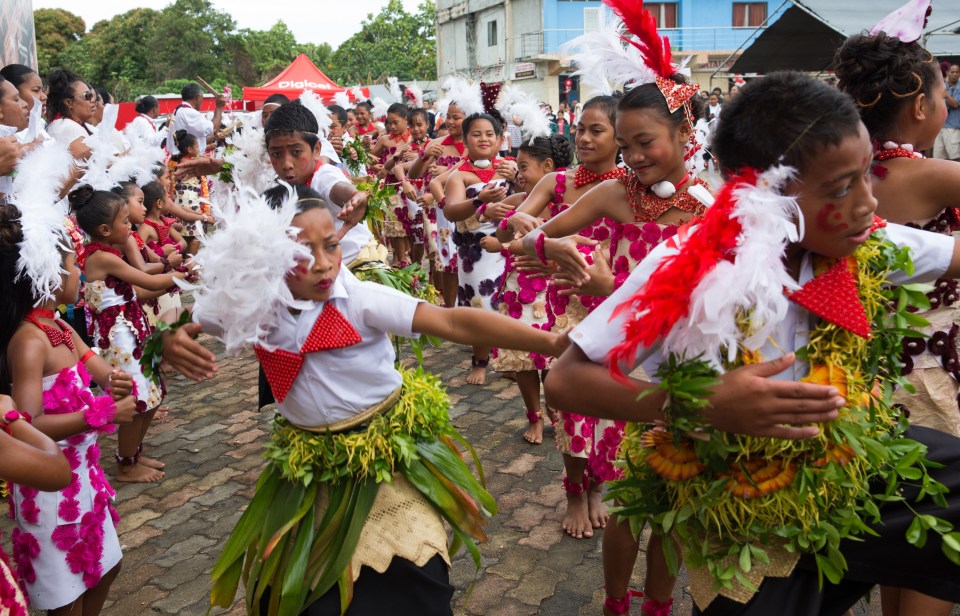 Children wearing traditional costumes celebrate the king's coronation in Tonga