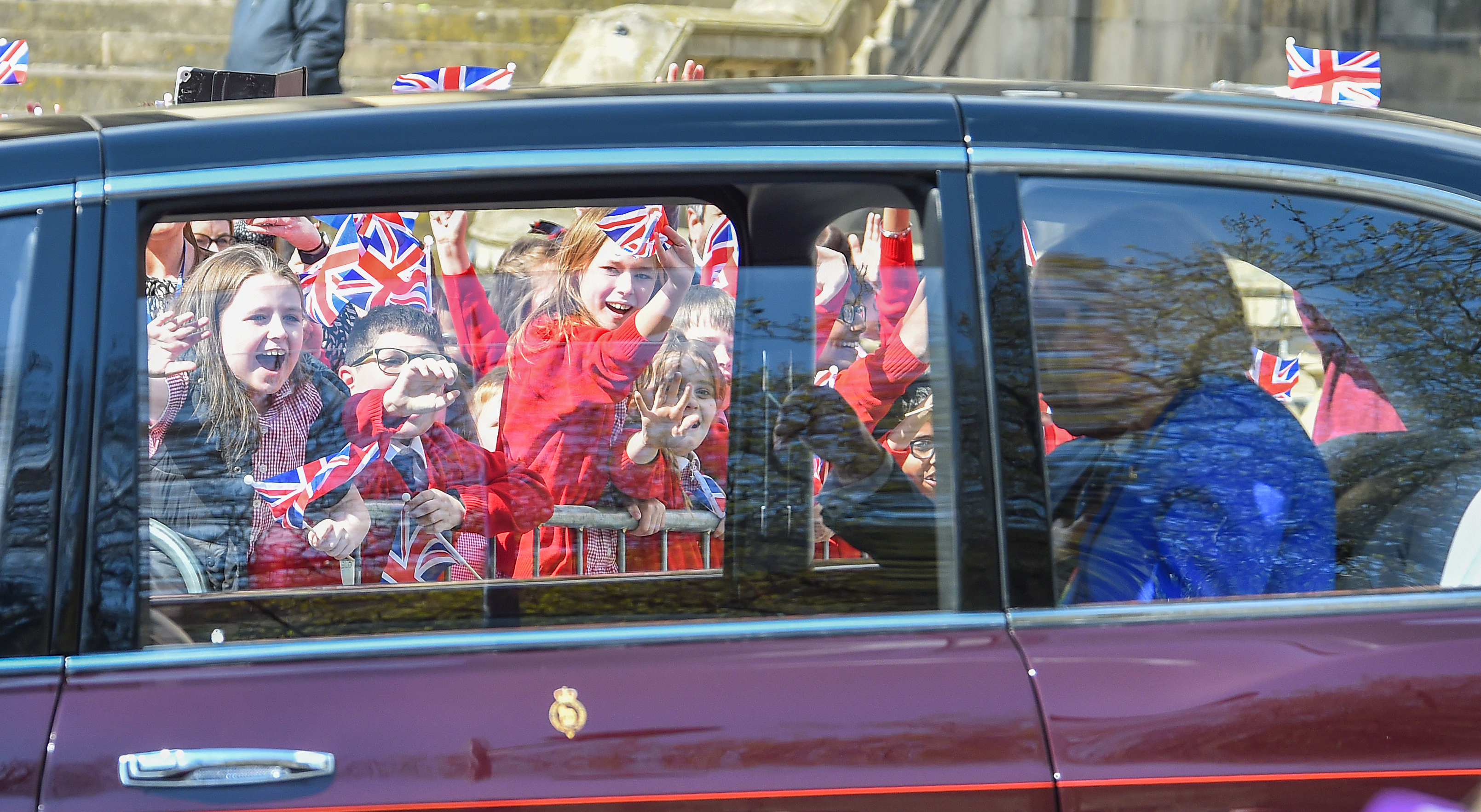 The children could be seen cheering and waving flags as the King and Queen Consort drove by