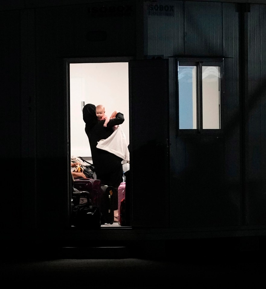 A woman holds her baby after arriving to Cyprus with 38 Britons rescued from Sudan