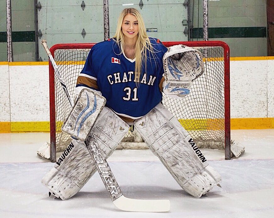 Mikayla posing in front of an ice hockey goal with her pads and stick