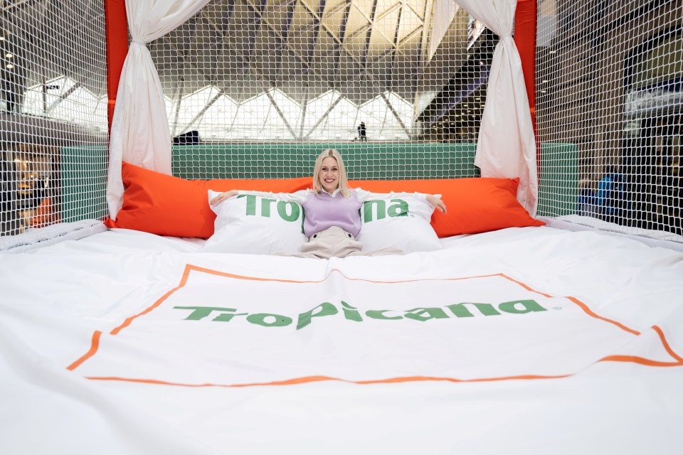 Annie Orchard, London commuter, jumps on a giant bed, installed by Tropicana in Kings Cross Station