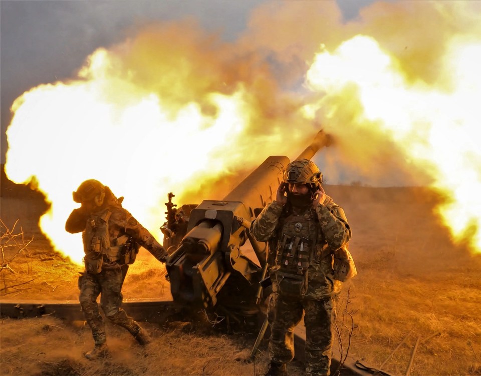 Ukrainian troops outside the city fire an artillery gun