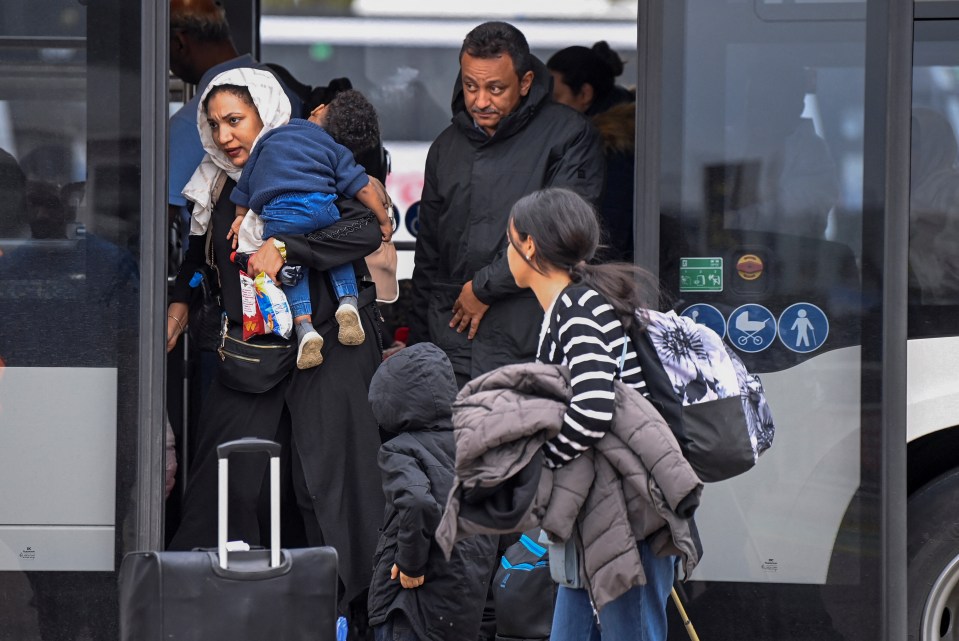 More evacuees disembark a bus at Stansted Airport