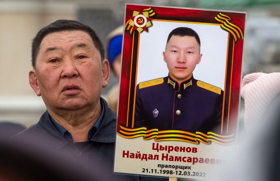 The father of a Russian army ethnic minority soldier from Buryatia holds up a picture of his dead son