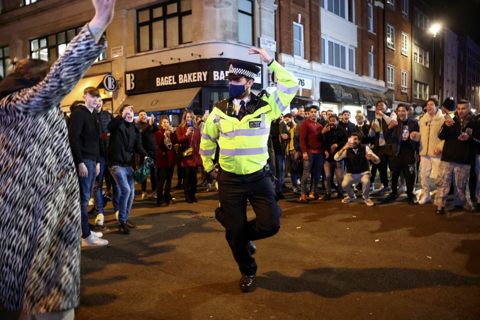 Policeman dances with people partying in the street after Covid restrictions were eased