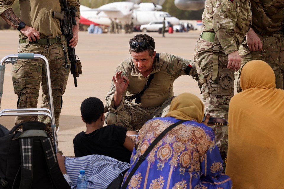 A Royal Marine checking on a child as they wait to board an aircraft for Cyprus