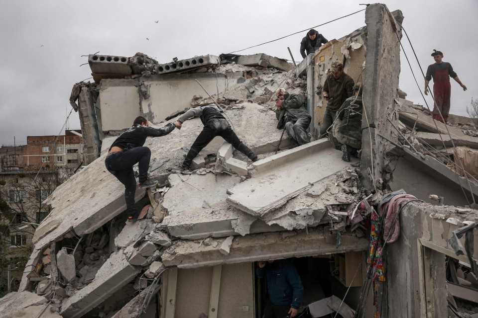 Rescuers and volunteers look for survivors on the top of a partially destroyed residential building after intense shelling in Sloviansk