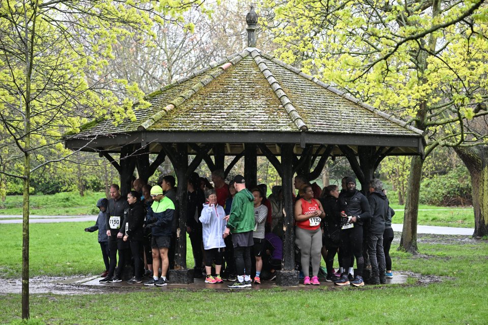 People shelter from the rain on Easter Monday in Regents Park, central London