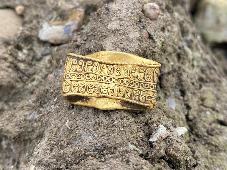 The ring is laden with red garnets that form a four-pronged star and is covered in intricate rope patterns