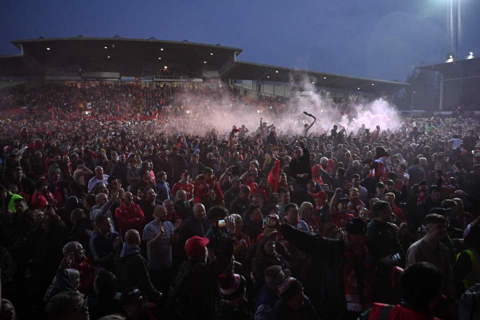 Fans celebrate their promotion on the pitch after victory over Boreham Wood.