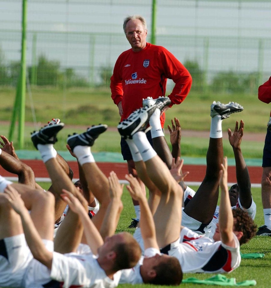 a man in a red shirt that says worldwide watches a group of soccer players stretching