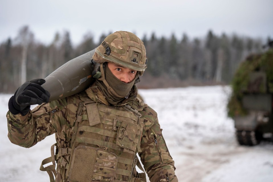 A British soldier carries a 155mm artillery shell