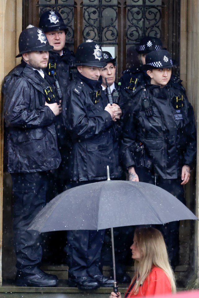 Police officers shelter from the rain outside Westminster Abbey as preparations for the coronation continue