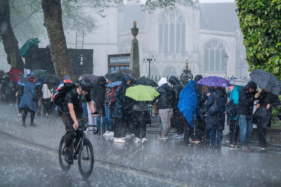 Pedestrians and royal fans are caught in a heavy downpour in Westminster today