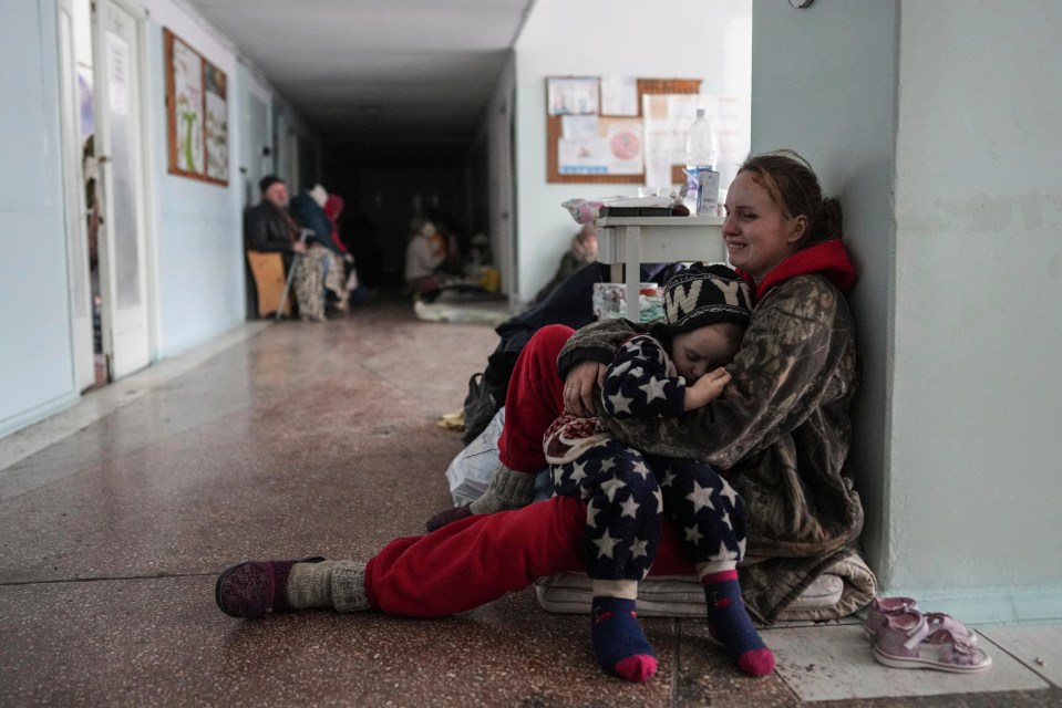 A mum cries as she holds her child on the floor of a hospital in Mariupol