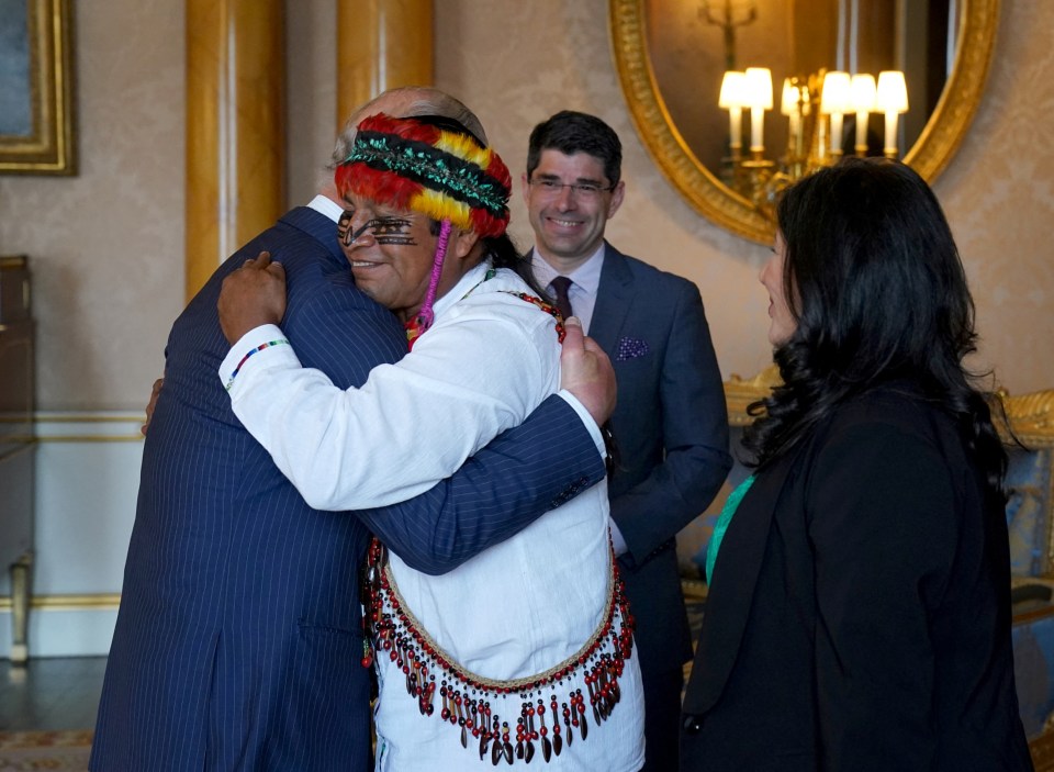 Uyunkar Domingo Peas, spokesperson for the Sacred Headwaters of the Amazon, gives the king a big hug