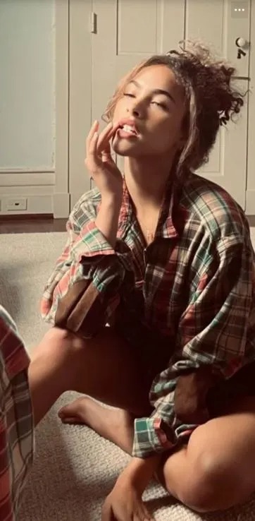 Woman in plaid shirt posing indoors.