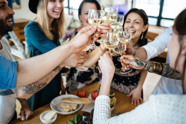 a group of people are toasting with wine glasses and one has a tattoo on his arm