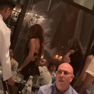 Lewis appears to smile as Shakira approaches his table at dinner in Miami