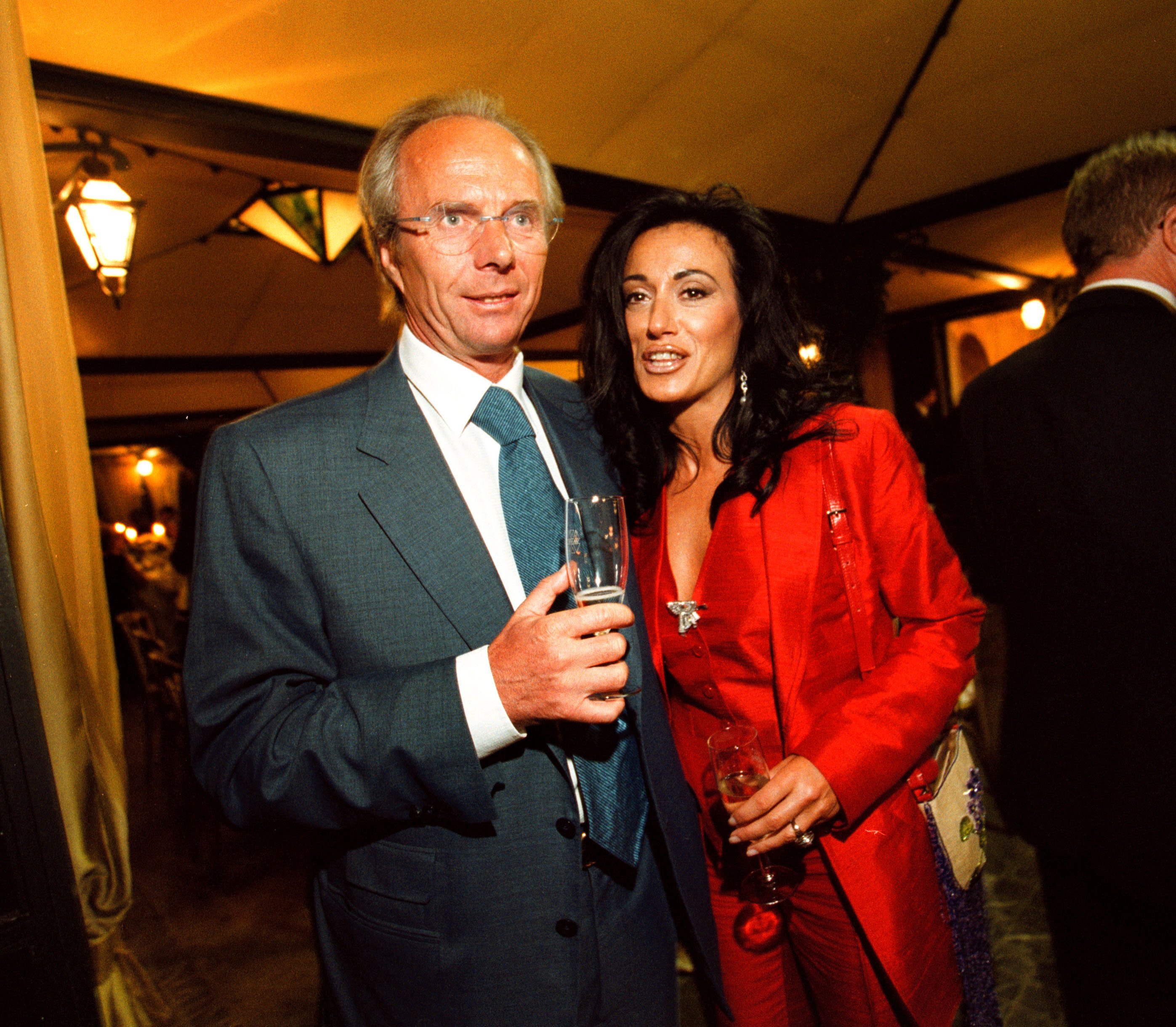 a man in a suit and tie stands next to a woman in a red dress