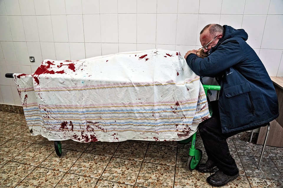 A father cries over the lifeless body of his teenage son