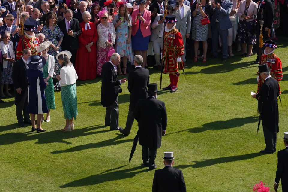 King Charles talks with a guest attending a Garden Party at Buckingham Palace