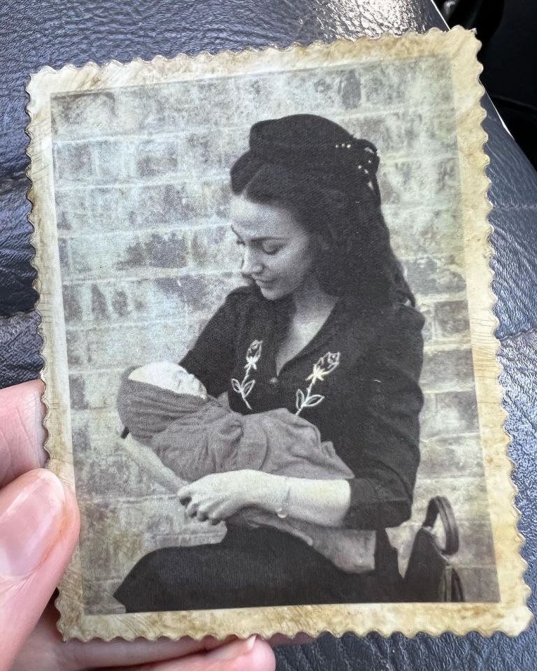 Another photo shows Michelle cradling a child while donning a little black statement hat and a black shirt dress with white flower embroidery