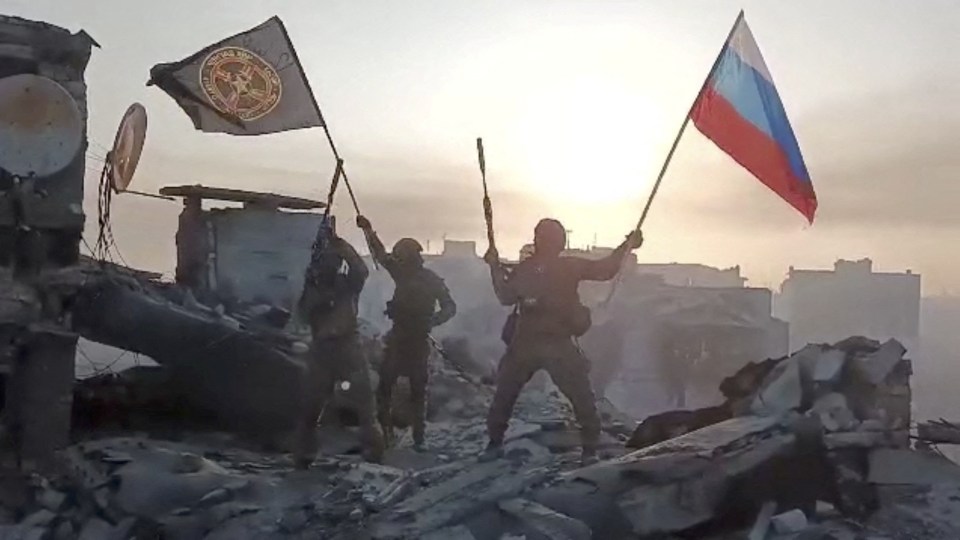 Wagner mercenary group fighters wave flags of Russia and Wagner in Bakhmut