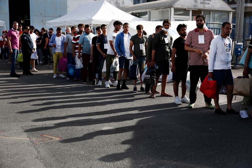 Migrants who survived the tragedy walk toward a bus that will take them from Kalamata port to a migrant reception facility in Malakasa