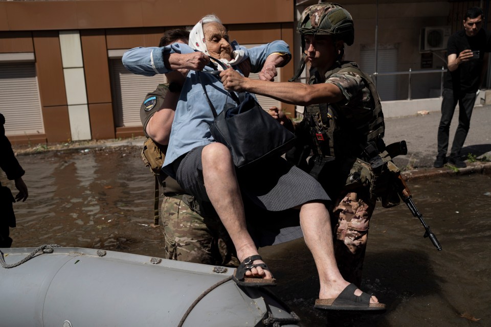 Soldiers help a woman out of a rubber dinghy