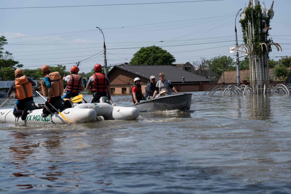 Ukrainian security forces transport local residents in a boat around the floods