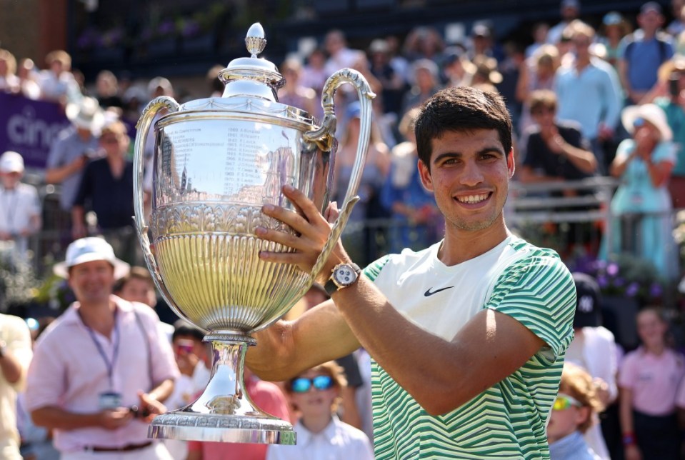 Carlos Alcaraz celebrates with the winner's trophy after victory at The Queen's Club