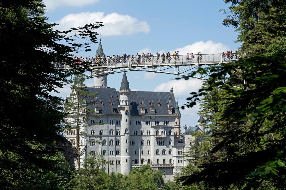 Tourists stand on the Marienbrücke Bridge near the Neuschwanstein Castle