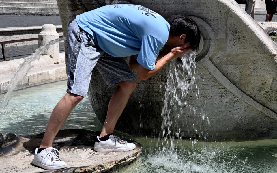 A tourist cooling off from Rome's stifling heat at the Trevi Fountain