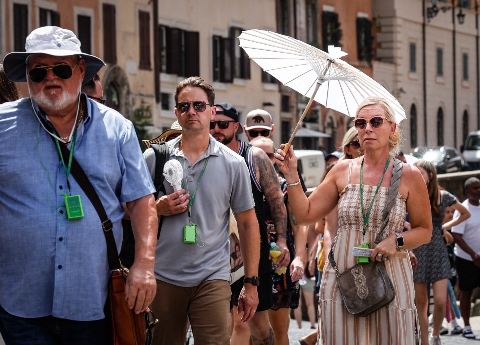 These people look hot and bothered in Rome as they shelter under parasols and hats