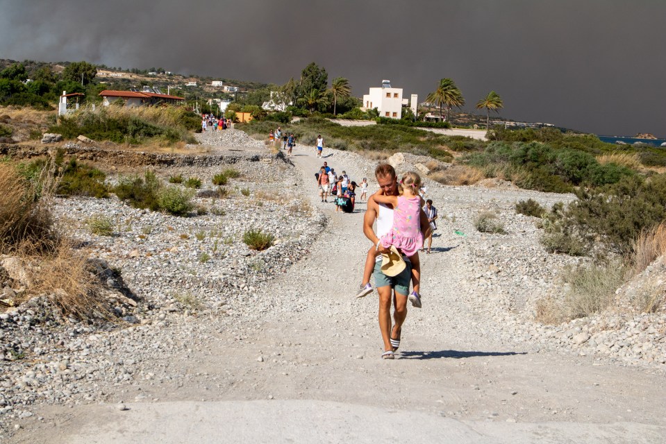 A man holds his child as they flee from a burning village