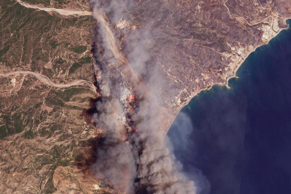 A satellite image from Planet Labs PBC shows the fires burning on Rhodes