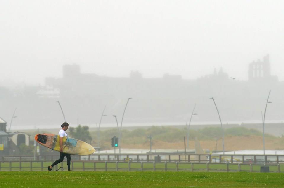 A surfer dashes to the stormy sea at Sandhaven Beach, Tyne & Weird, on Monday