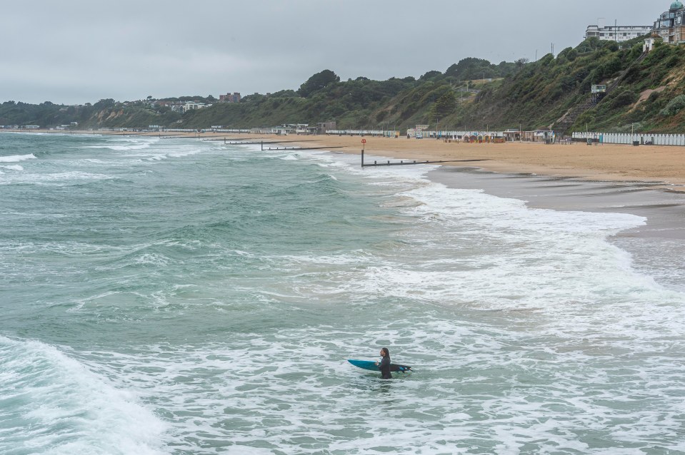 A brave surfer heads into the water to catch some waves on stormy Bournemouth Beach, Dorset, on Monday morning